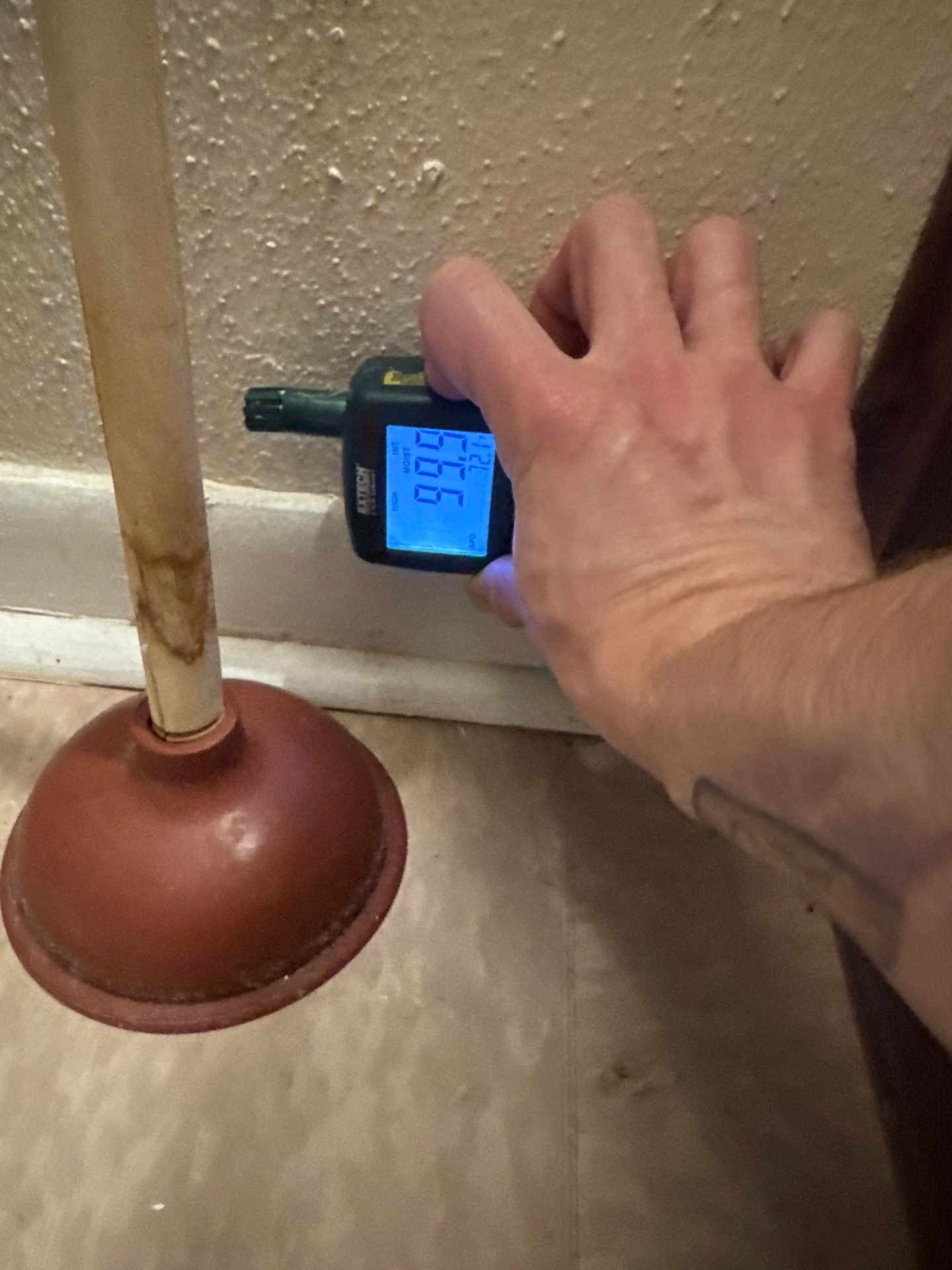 Moisture meter reading at baseboard confirming elevated moisture levels