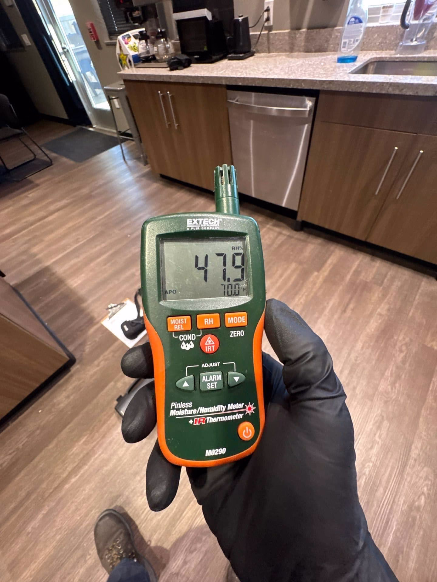Moisture meter reading taken on kitchen wall showing hidden humidity behind cabinets