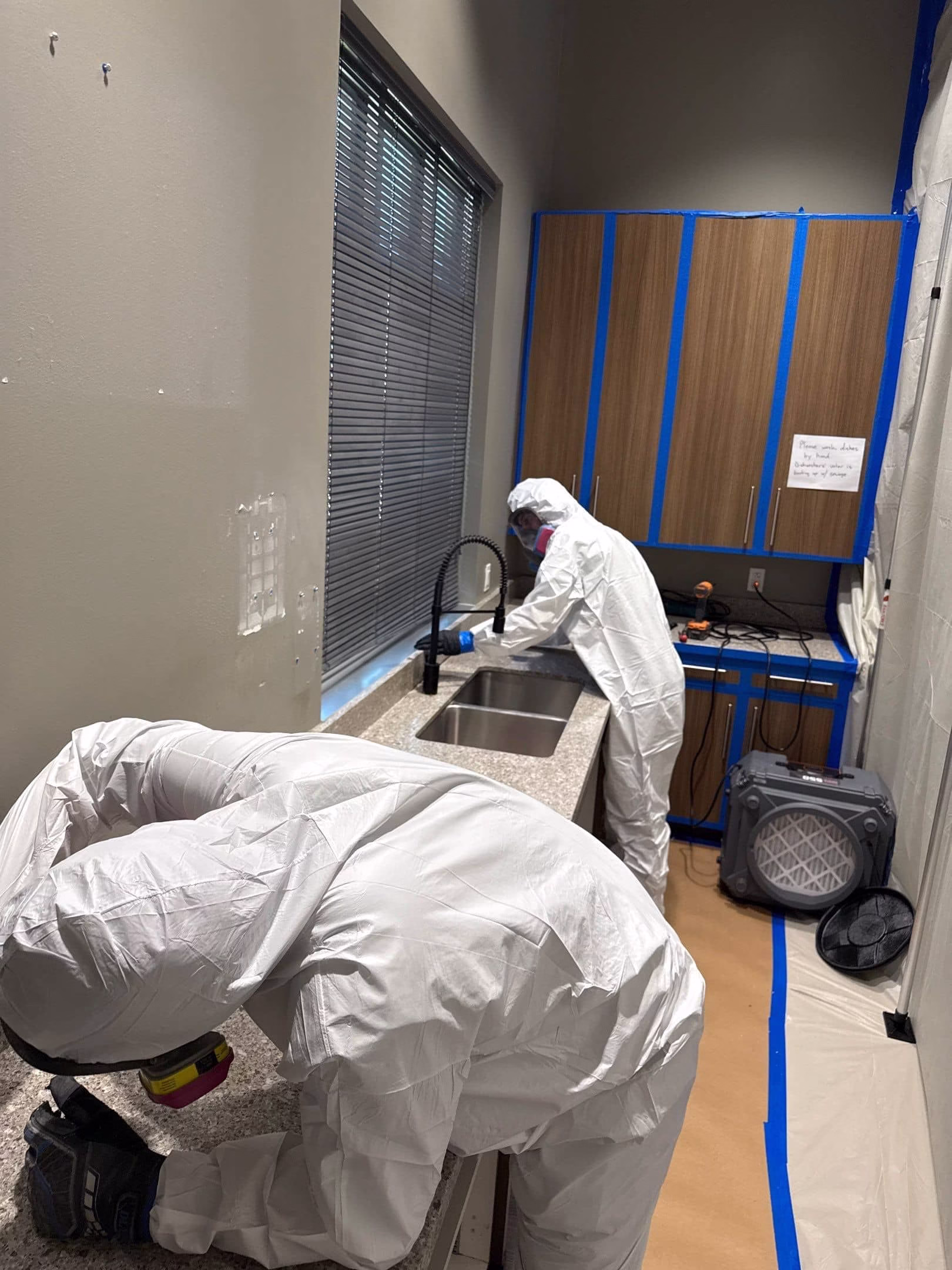 Austin Fire and Flood technicians in full Tyvek PPE suits and respirators during kitchen mold remediation