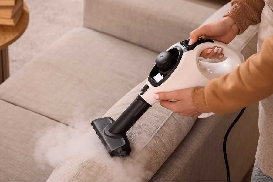 Steam cleaner treating a fabric sofa to remove smoke odor and residue in an Austin TX living room