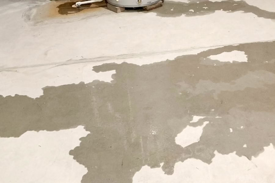 Standing water on a concrete basement floor with visible water line on foundation walls, stored boxes and shelving partially submerged