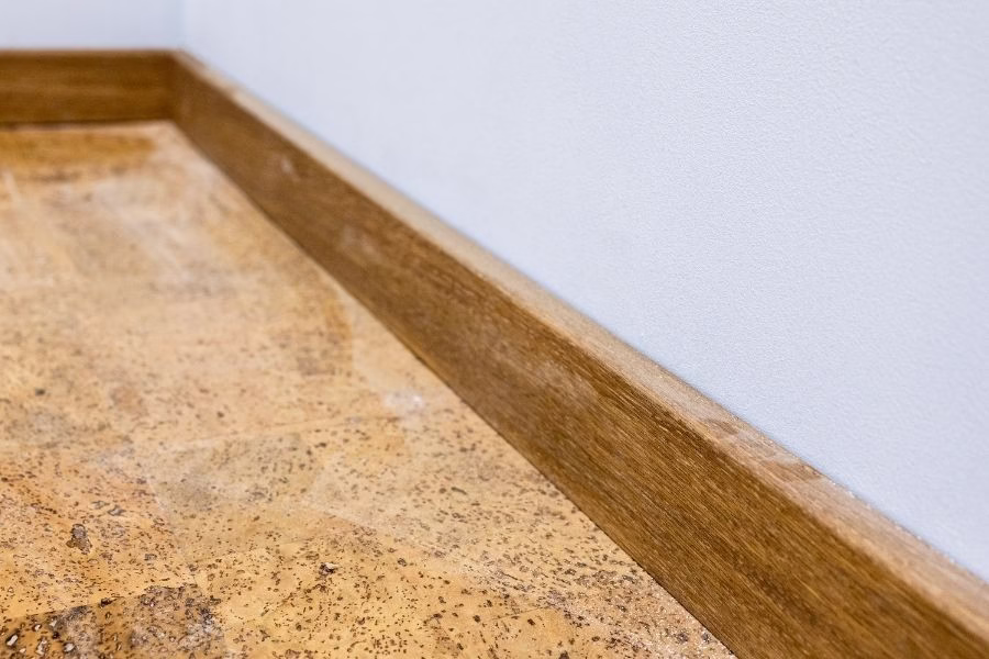 Technician removing wet baseboards in a bathroom with standing water near the toilet base, moisture meter in hand