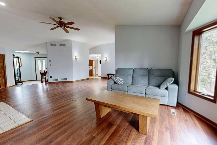 Newly installed hardwood flooring in a restored living room, clean transition to adjacent tile, bright natural light from windows