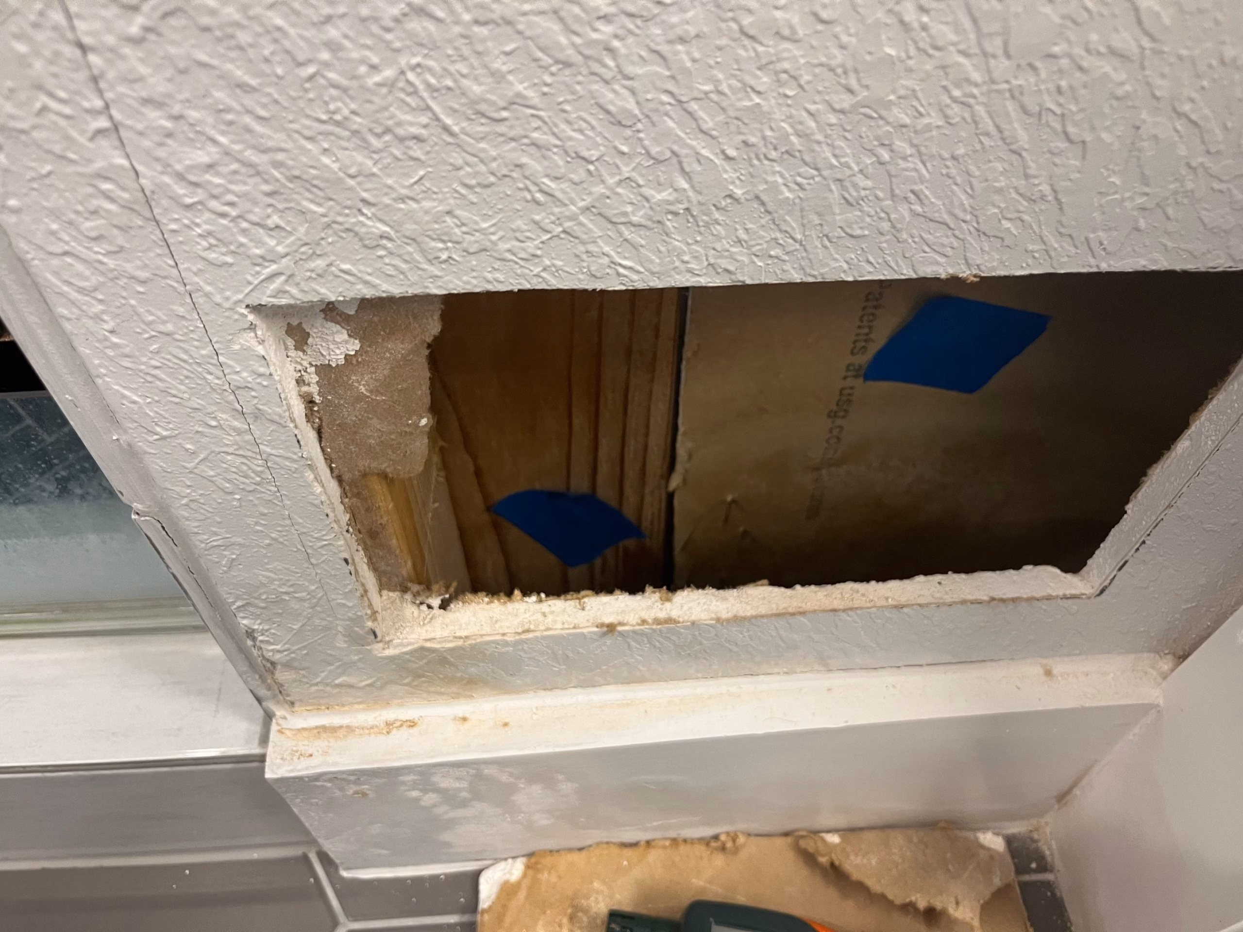 Exposed ceiling cavity revealing the extent of hidden water damage behind the bathroom wall
