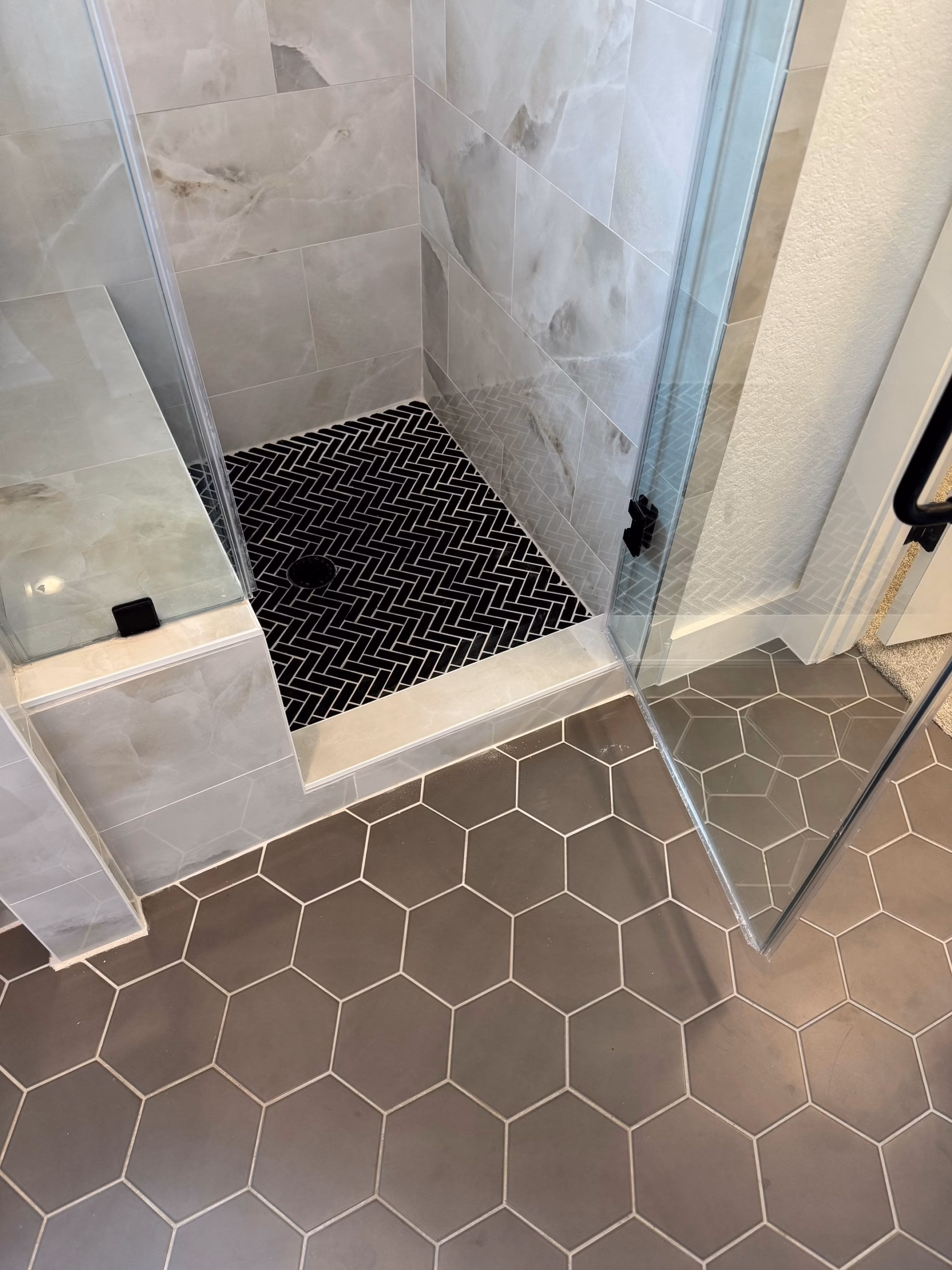 Finished walk-in shower with herringbone floor tile in an Austin home