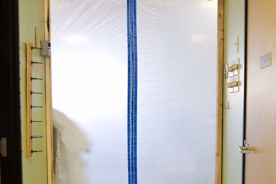 Plastic containment barrier and HEPA air scrubber set up during a mold remediation job
