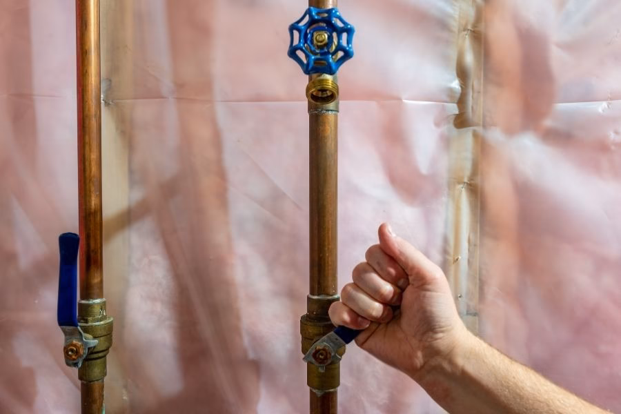 Homeowner turning off the main water shutoff valve before leaving on summer vacation
